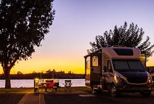 rv parked at a campsite on the water at sunset